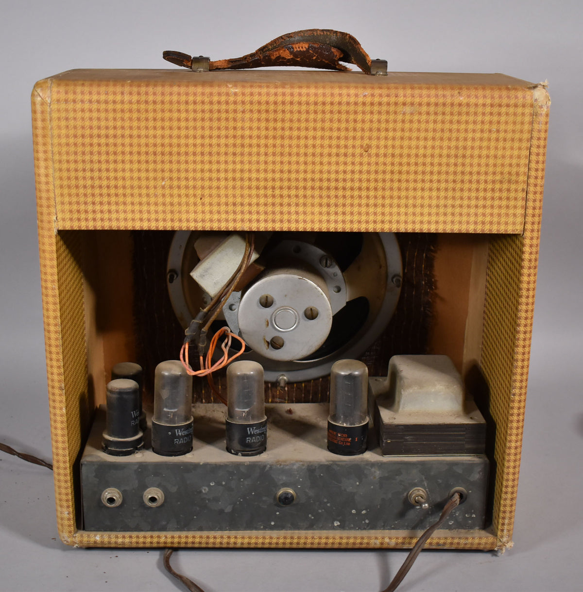 Rear view of the tweed-covered amplifier, showing the exposed speaker, four vacuum tubes, and the worn leather handle.
