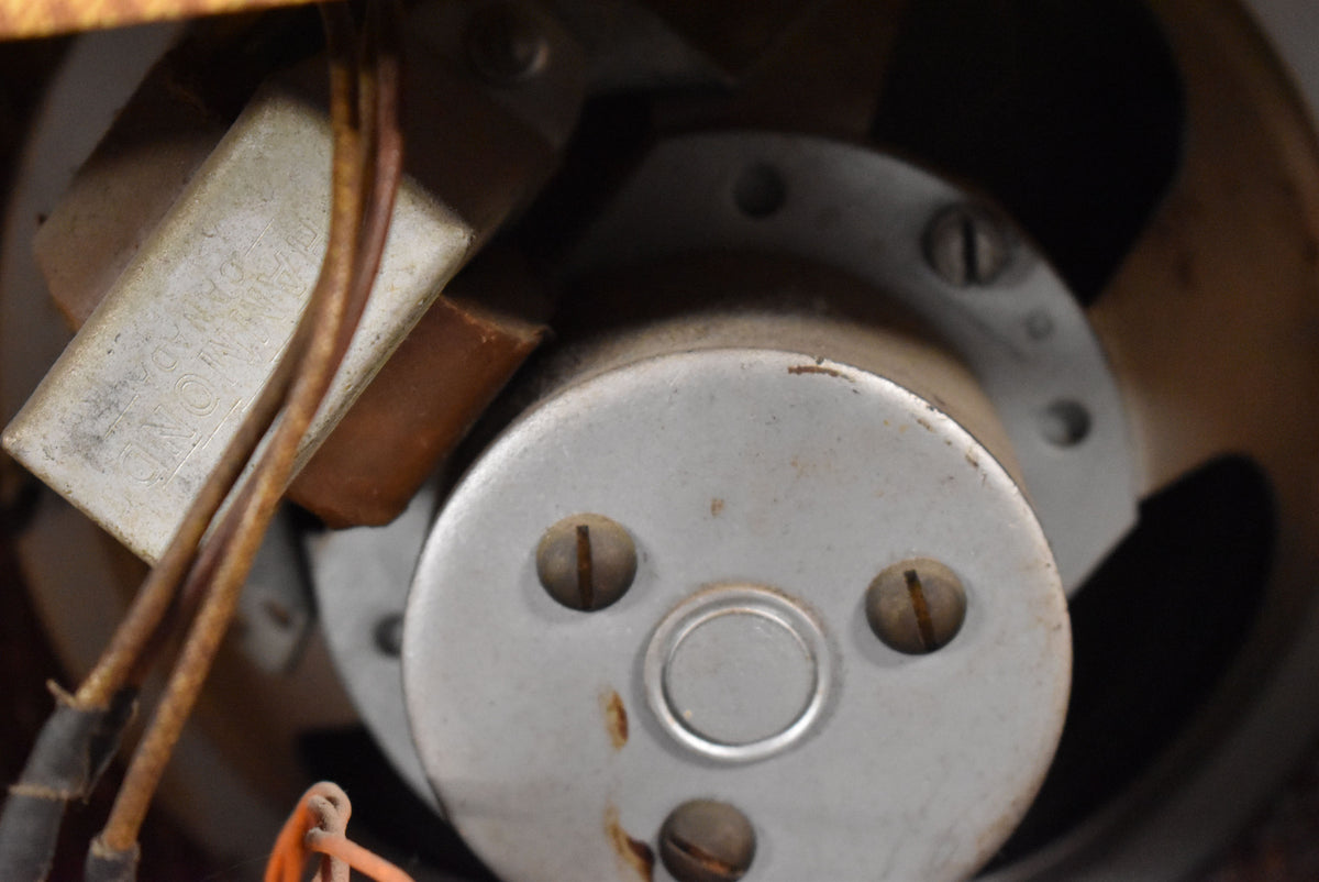 Close-up of the amplifier's internal components, showing a silver-grey metal cylinder with three screws and a smaller silver rectangle.