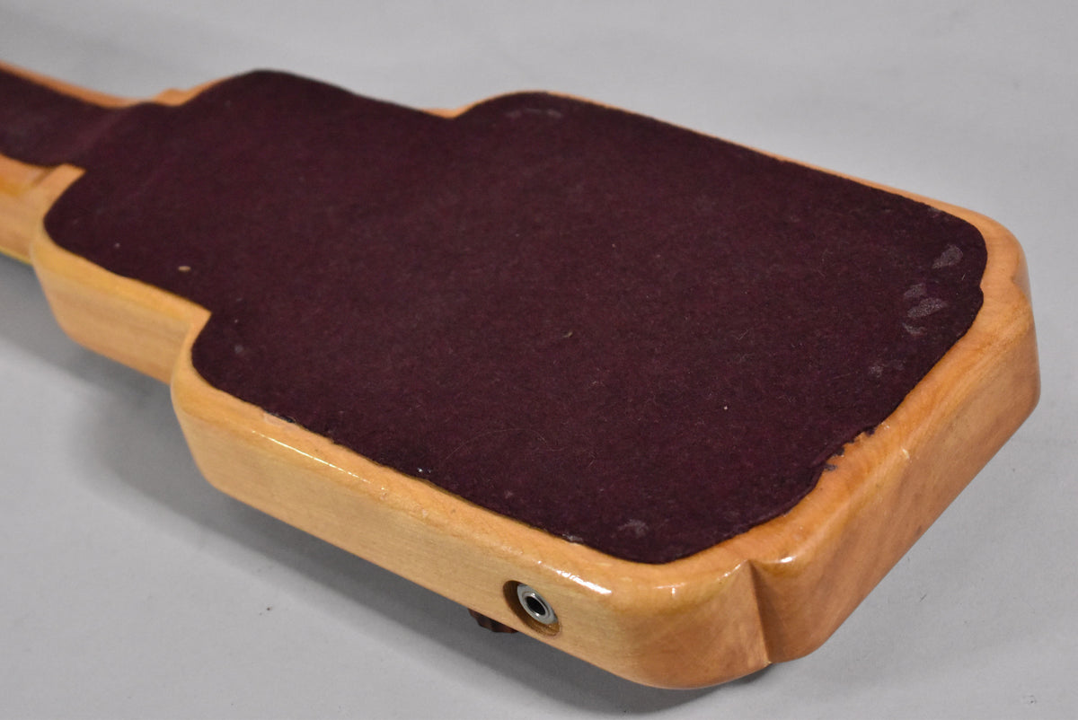 The lapsteel's underside, angled from the back, shows a light wood body with a dark red felt pad and a chrome output jack.