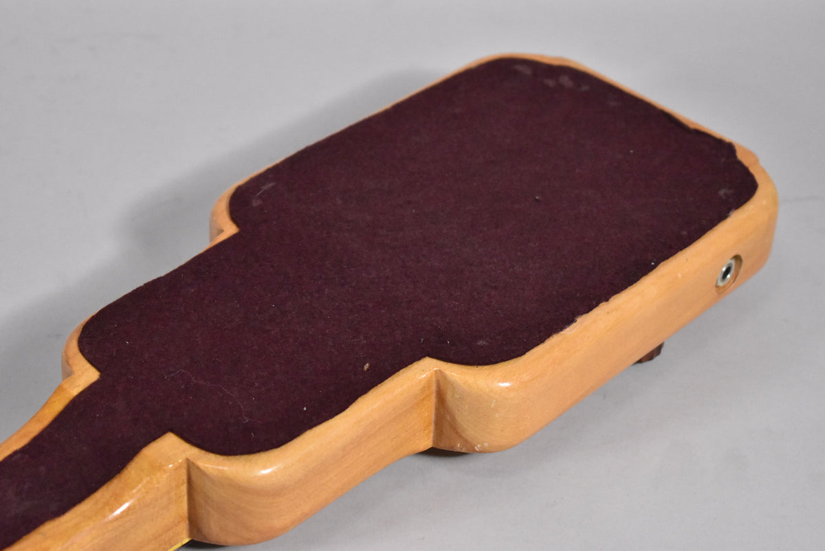 The lap steel's natural wood underside, with a dark red felt pad and a chrome output jack, shows minor wear and finish checking.