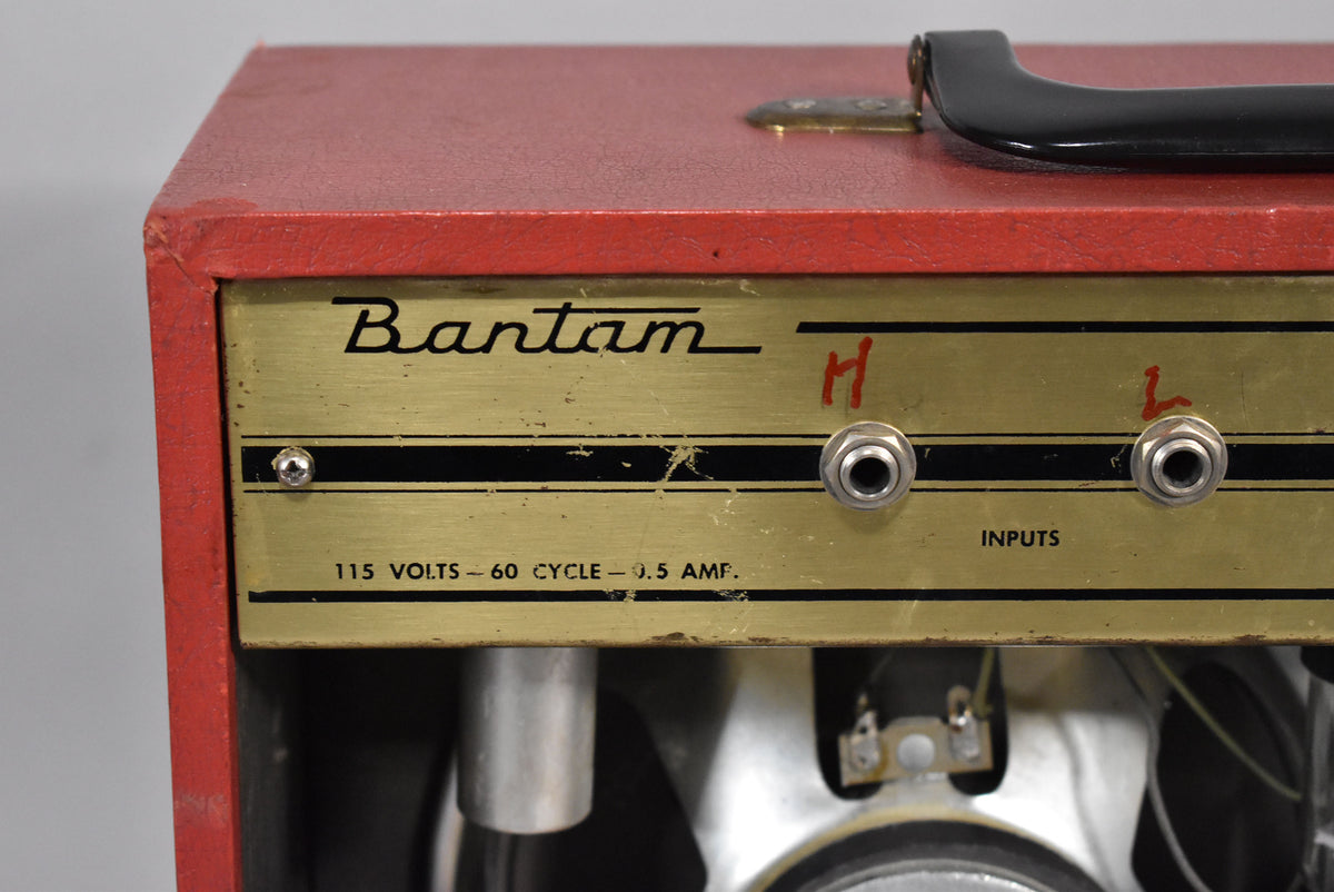 Close-up of the red amp's gold control panel, showing two input jacks labeled "H" and "L" in red marker, and visible wear.