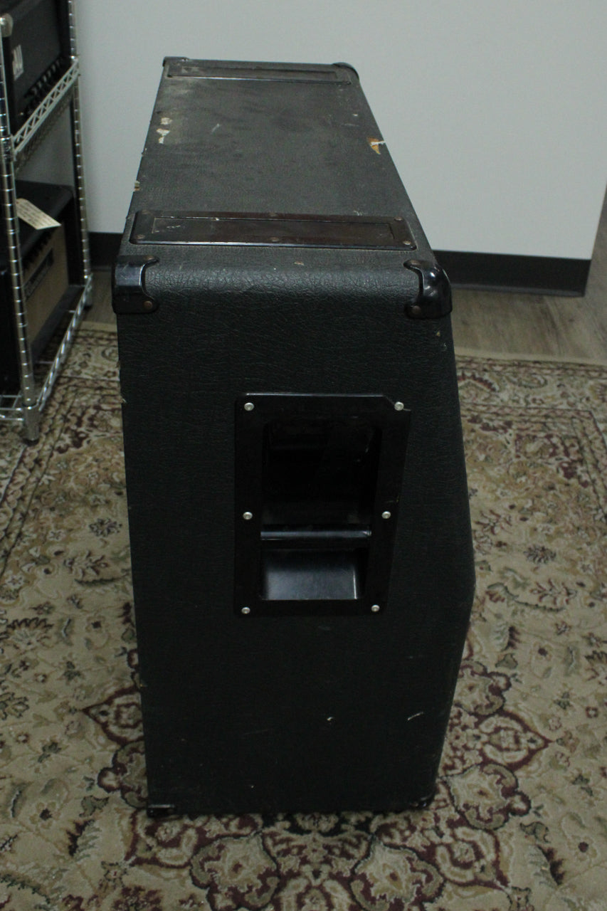 The black textured cabinet is viewed from the top-right, showing a recessed side handle and worn top surface with scuffs and scratches.
