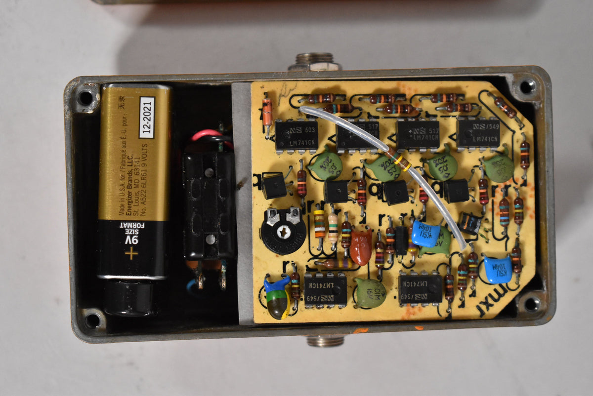 Overhead view of the pedal's open back, revealing a 9V battery, battery clip, and a yellow circuit board with various components.