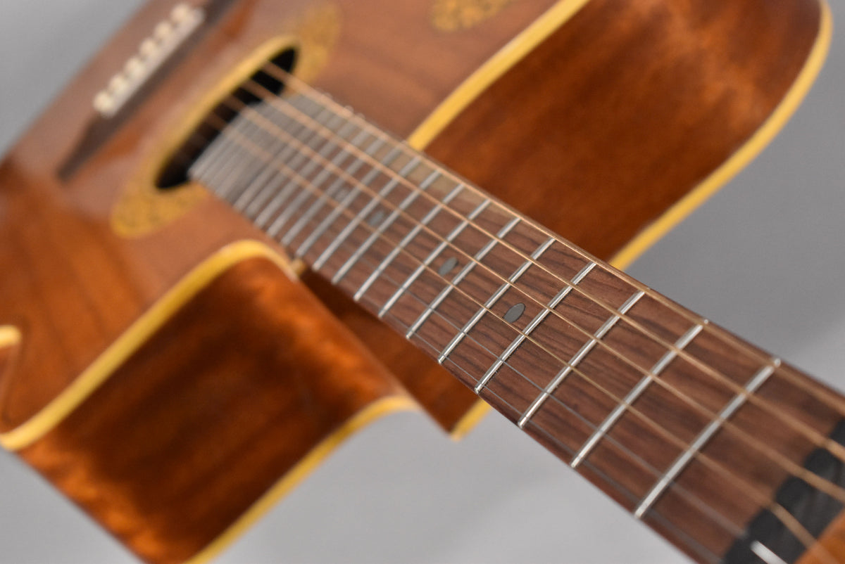 Close-up of the natural finish acoustic guitar's fretboard and lower bout, showing light wear on the frets and body binding.