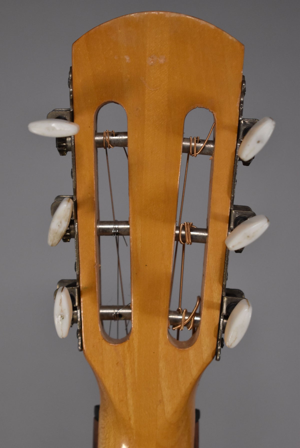 The back of the guitar's headstock, showing six white tuning pegs, three on each side, with visible wear and grime.