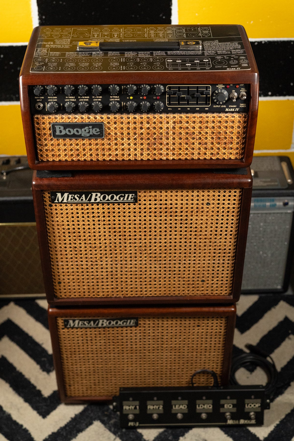 Full front view of a dark wood amplifier head with a wicker grille, stacked on two matching 1x12" speaker cabs.