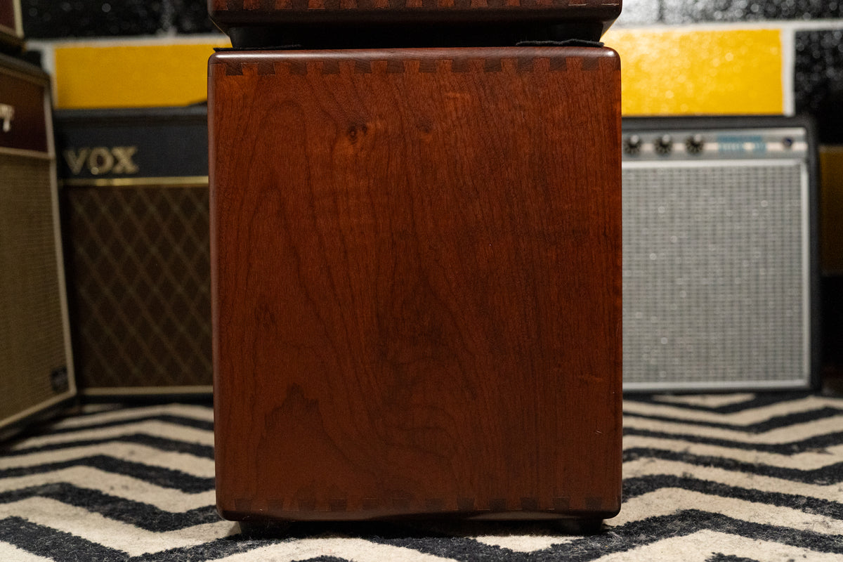 The side of a dark reddish-brown wooden cabinet, showing dovetail joints at the top and bottom edges, with minor scuffs.