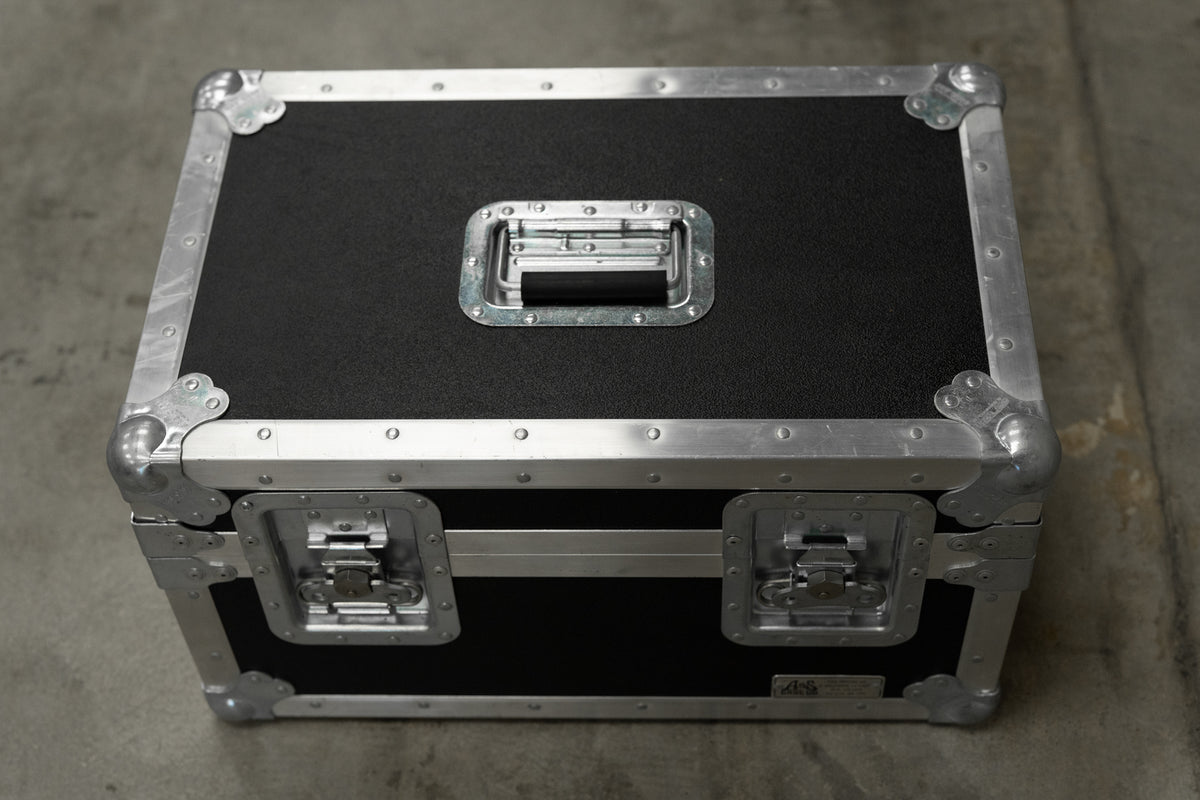Roadcase with black textured panels, aluminum edging, and chrome hardware, including a top handle and two front latches.