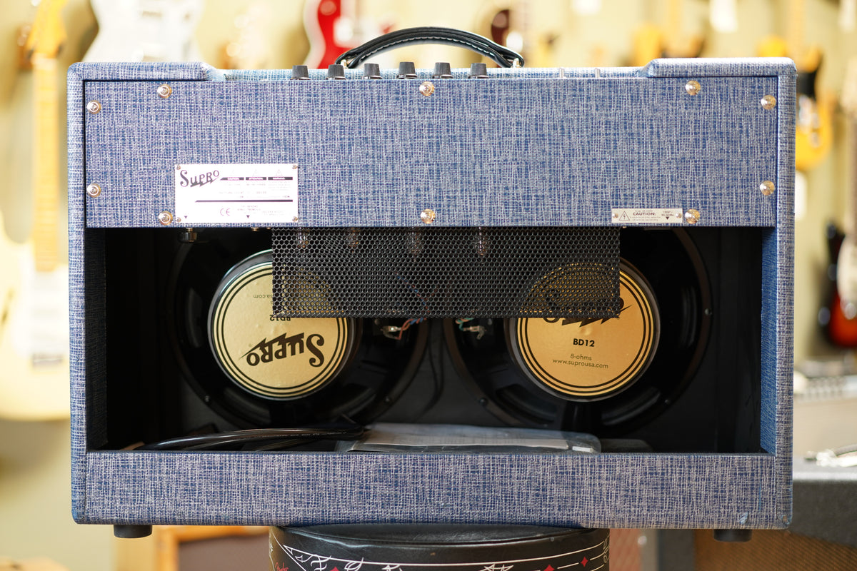 Rear view of the blue tweed combo amp, showing two gold-coned speakers behind a black mesh and a metal label on the top left.