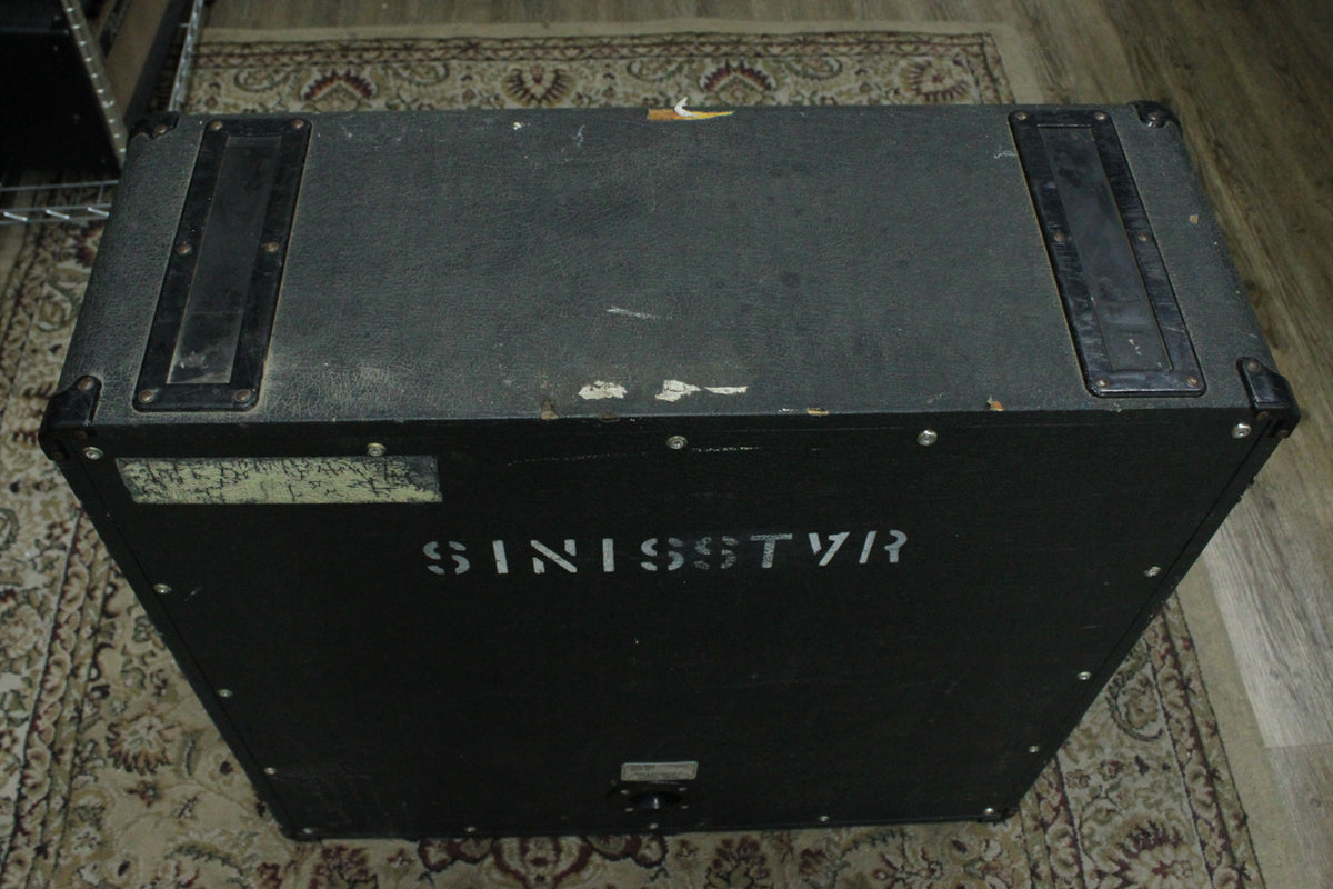Top-down view of the black cabinet, showing two recessed handles, metal corner protectors, and "SINISSTVR" stenciled on the side.
