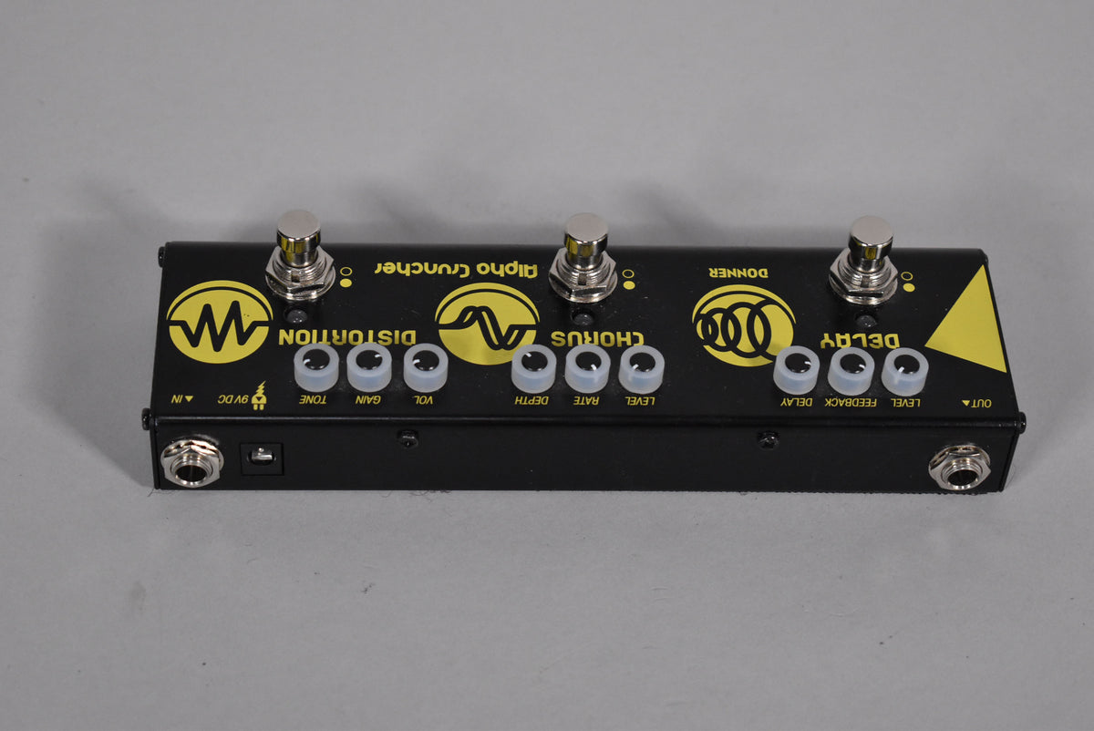 Black multi-effects pedal with three silver footswitches, nine clear mini-knobs, and yellow graphics, viewed from above.