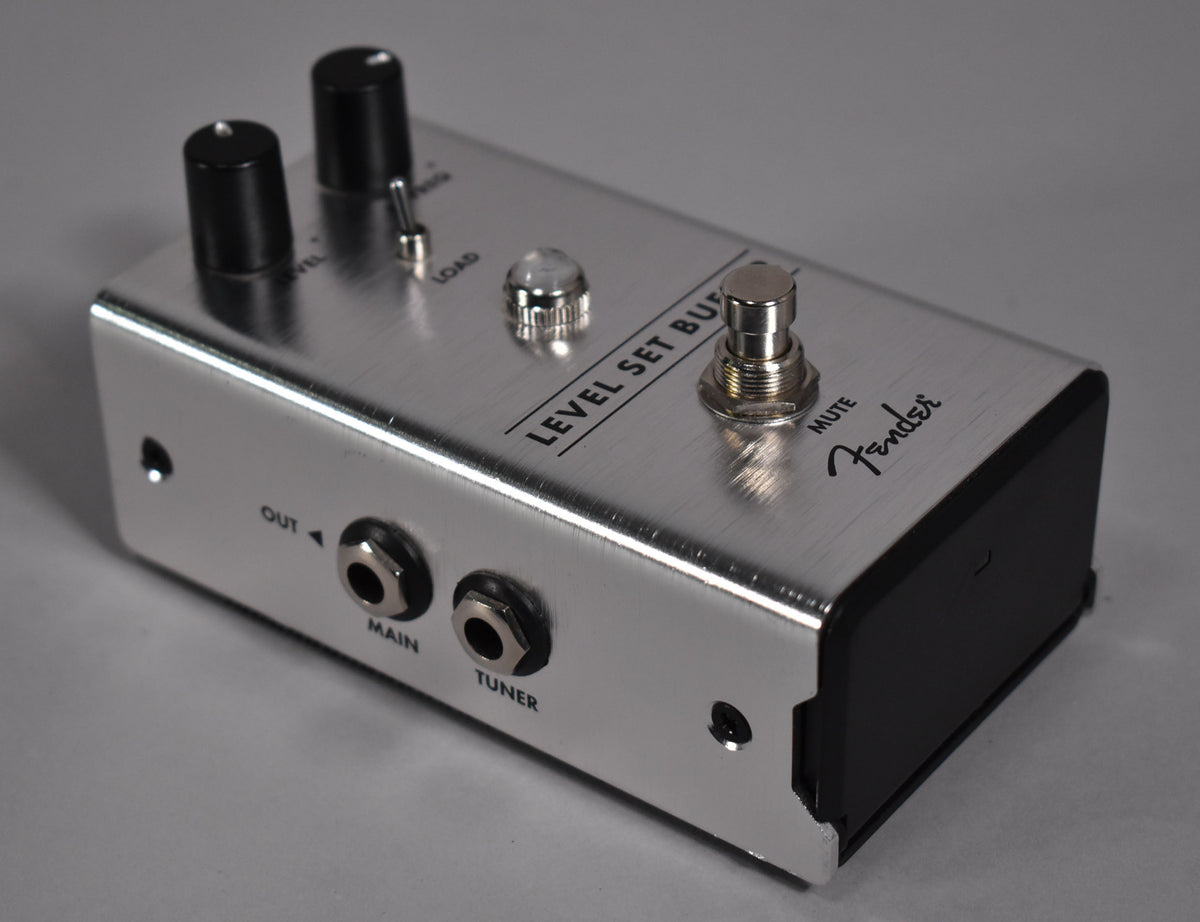 The brushed aluminum pedal is angled from the right, showing two black knobs, a toggle switch, a clear jewel light, and a footswitch.