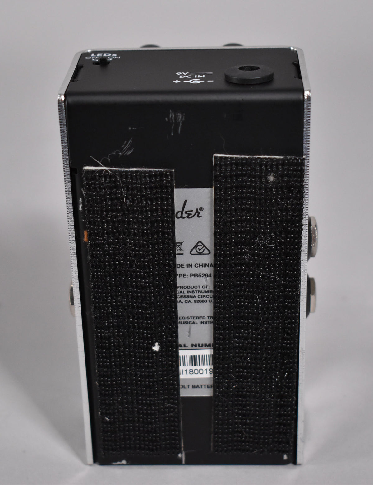 The pedal's black rear panel, with a 9V DC input and two strips of black hook-and-loop tape, shows scuffs and wear.