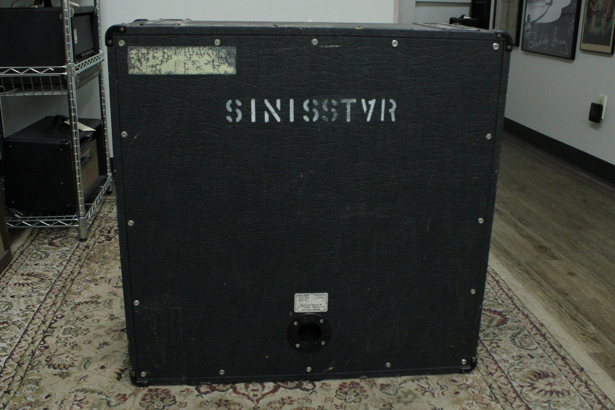 Rear view of a black textured cabinet with "SINISSTVR" stenciled in white, a worn label, and a single input jack.