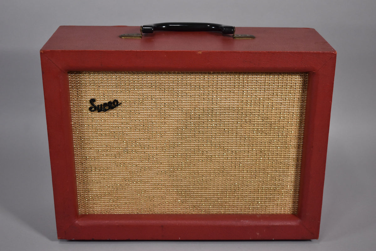 Front view of a red combo amp with a gold sparkle grille cloth, black handle, and minor wear on the top edges.