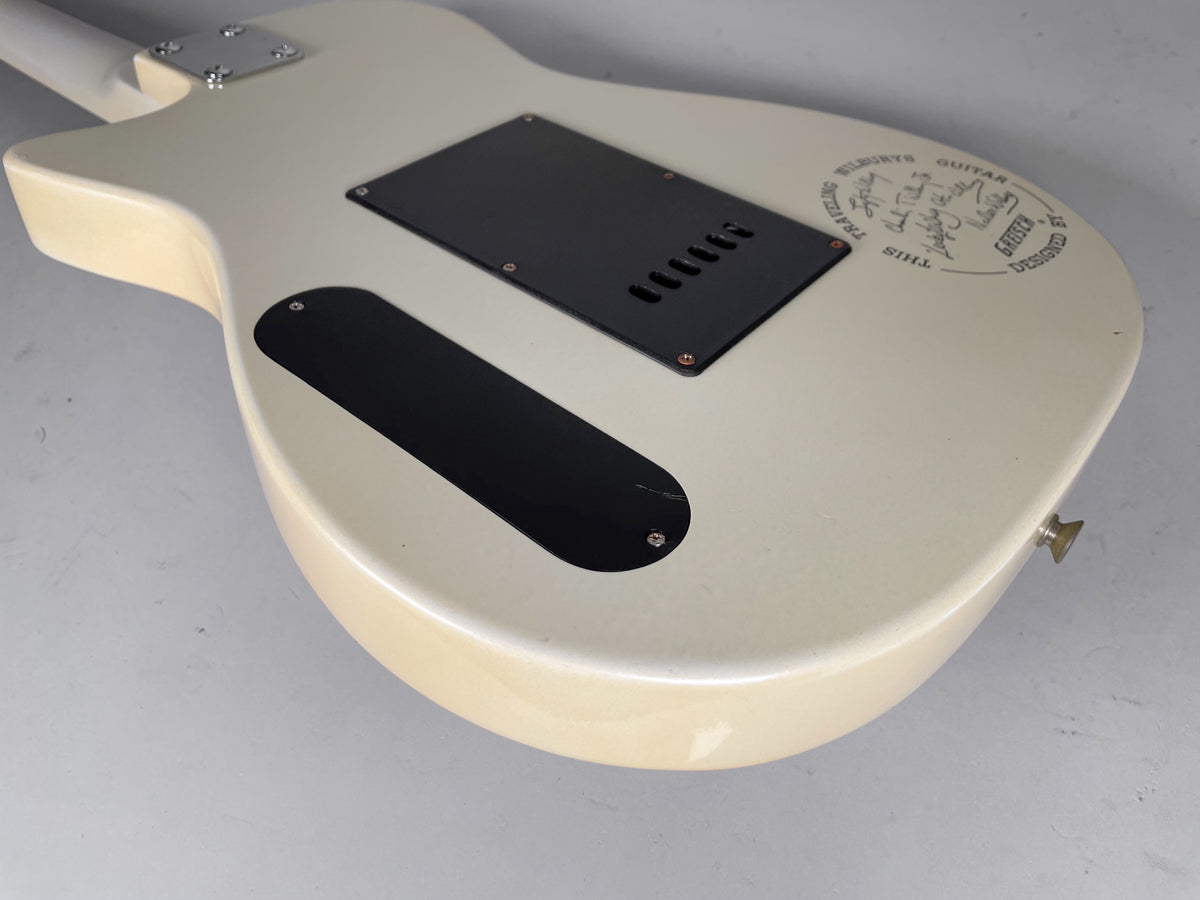 Rear view of the off-white guitar body, showing two black control cavity covers and a circular graphic with signatures.