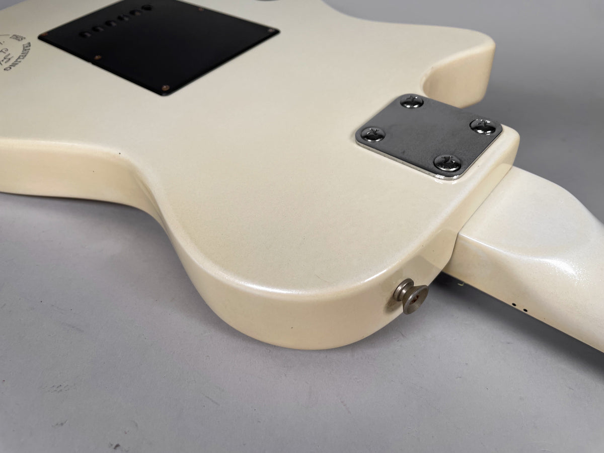 The back of the off-white guitar body shows a black control cavity cover, a chrome neck plate, and a strap button.