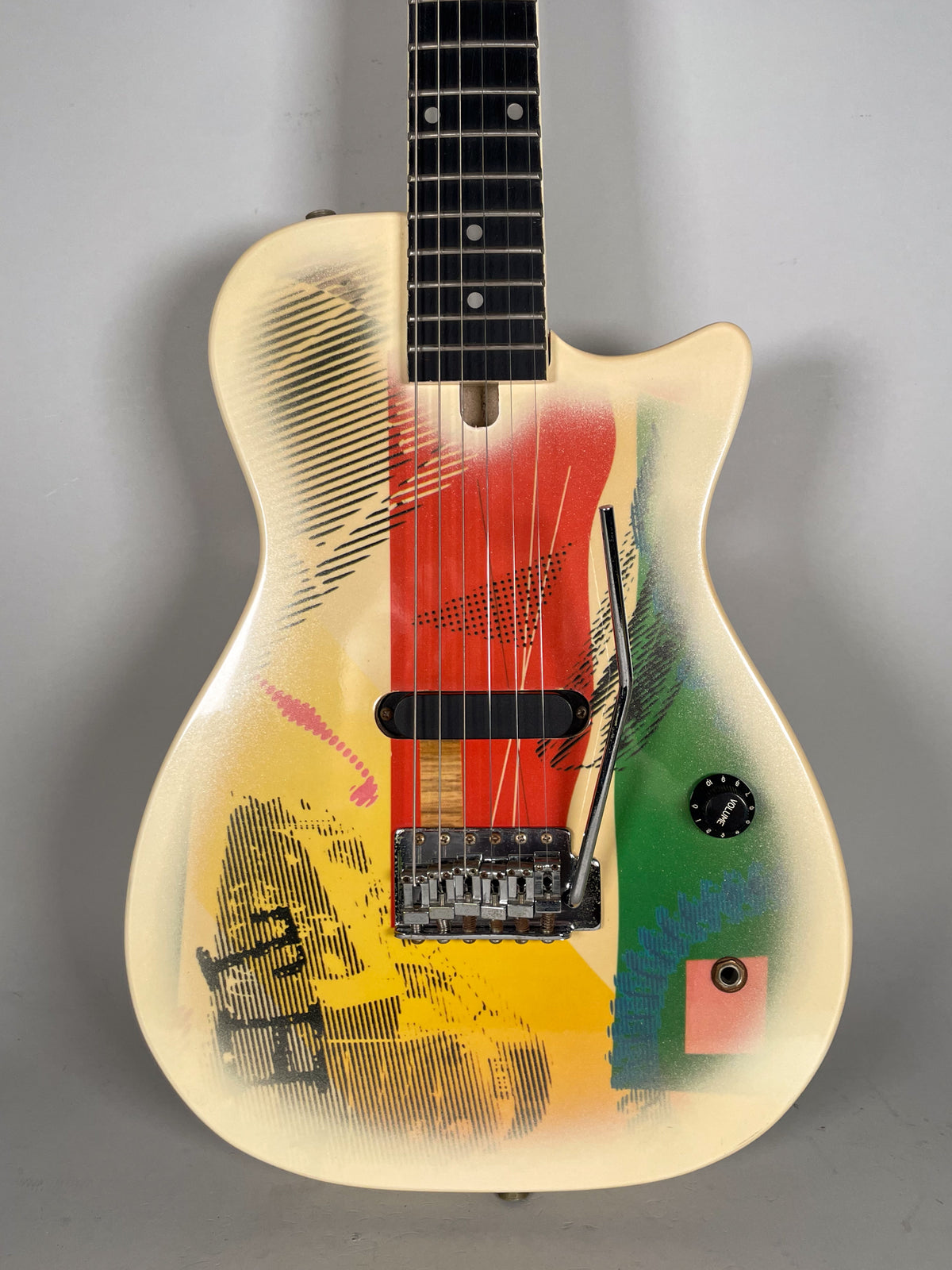 Full front view of a cream electric guitar with a vibrant abstract art finish, a single black pickup, and a tremolo system.