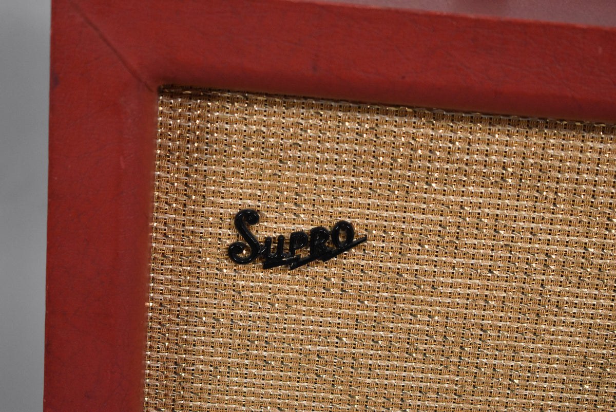 Close-up of the amp's upper right corner, showing the red cabinet with some wear and a gold grille cloth with a black script logo.