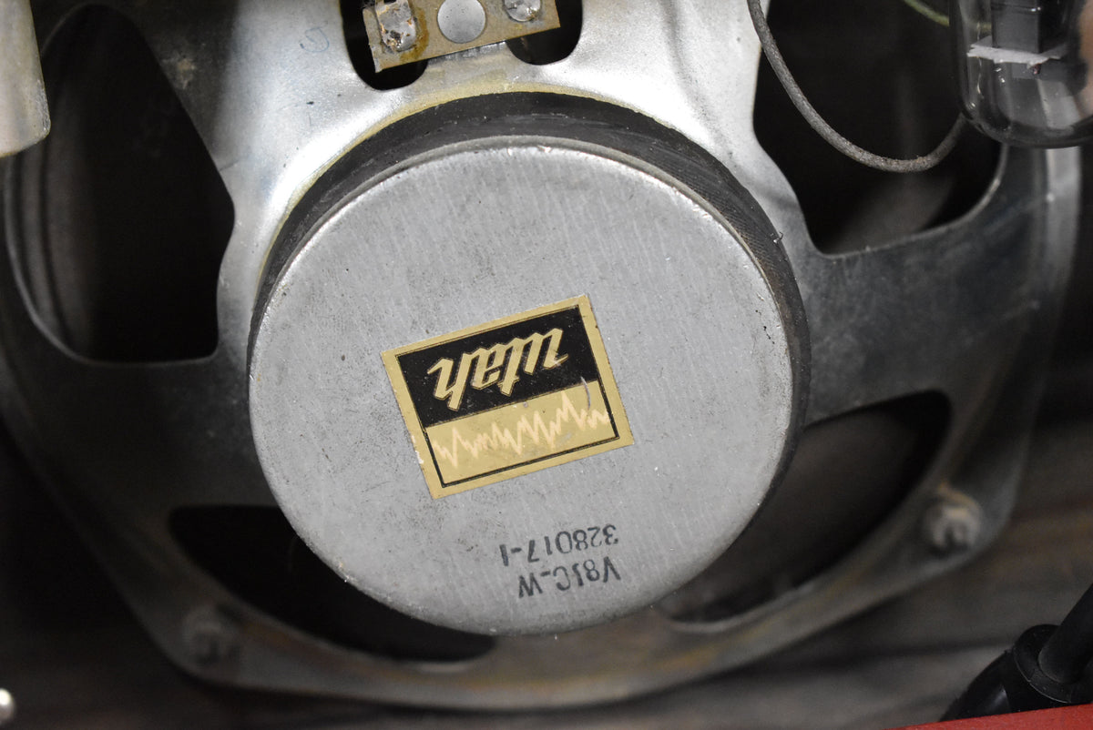 Close-up of the amplifier's silver speaker magnet, with a gold and black label and stamped numbers, showing some wear and dust.
