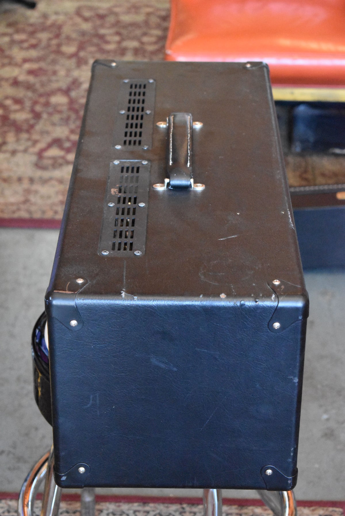 The black amplifier head is seen from above, showing the top with two vented grilles, a handle, and some scuffs.
