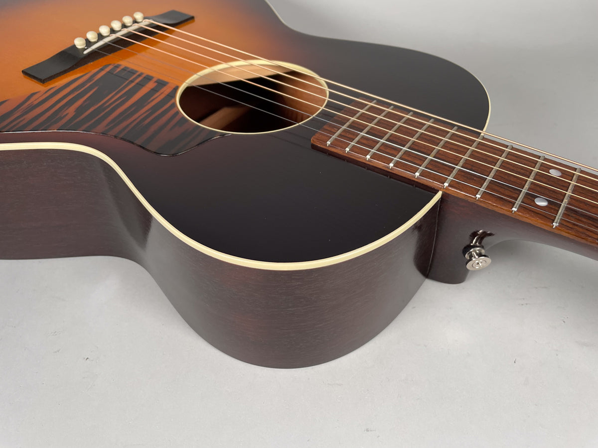 Upper body of a sunburst acoustic guitar, angled from the lower bout to the neck heel, showing the dark brown back and sides.
