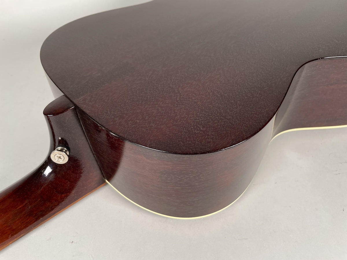 Close-up of the guitar's dark sunburst body and neck heel, showing the strap button and cream binding along the lower bout.