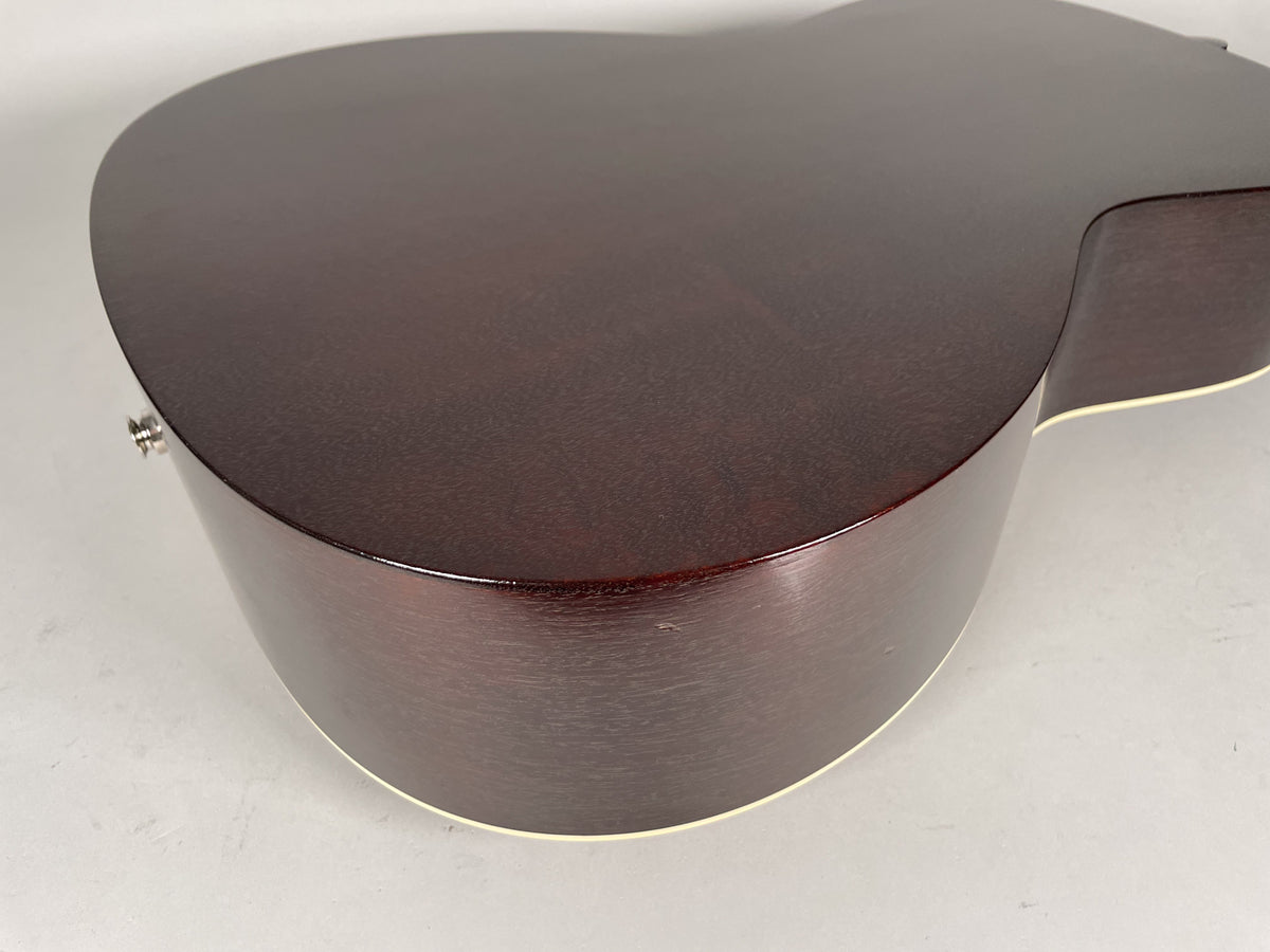Close-up of the dark sunburst acoustic guitar's lower bout and side, showing a subtle scratch on the side and cream binding.