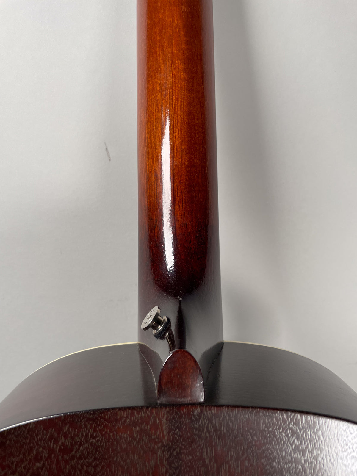 The guitar's dark sunburst neck heel and lower neck are shown from the back, with a chrome strap button visible.