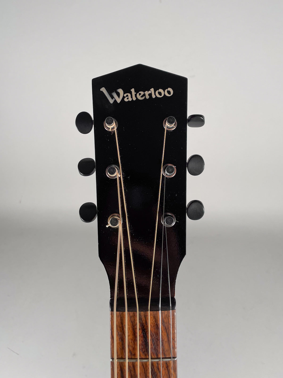 The guitar's black headstock, with six black tuning pegs, is centered, showing the top of the fretboard and strings.