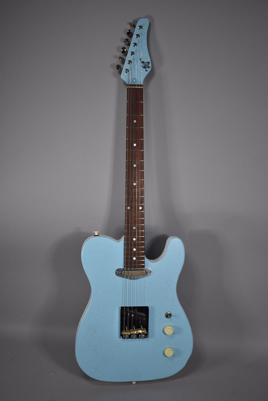 Full front view of a light blue sparkle electric guitar with a dark fretboard, chrome tuners, and cream control knobs.