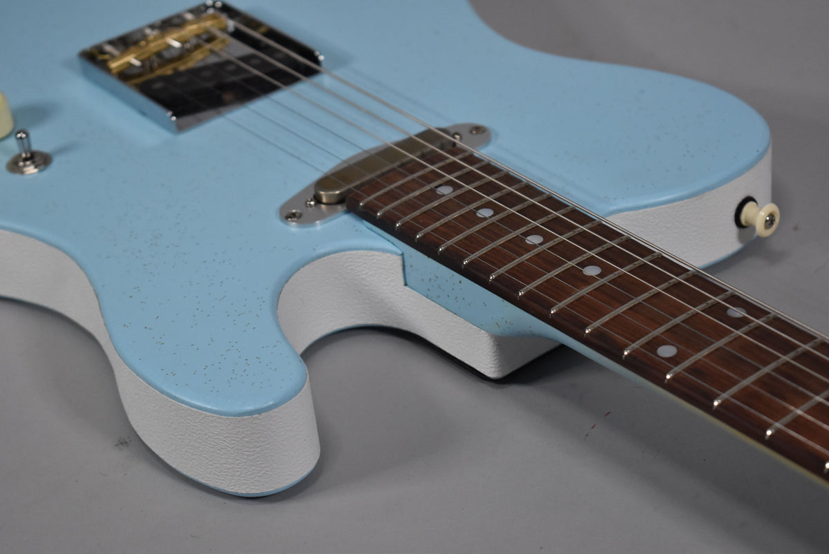 Close-up of the light blue guitar body with a textured finish, white sides, and rosewood fretboard with dot inlays.
