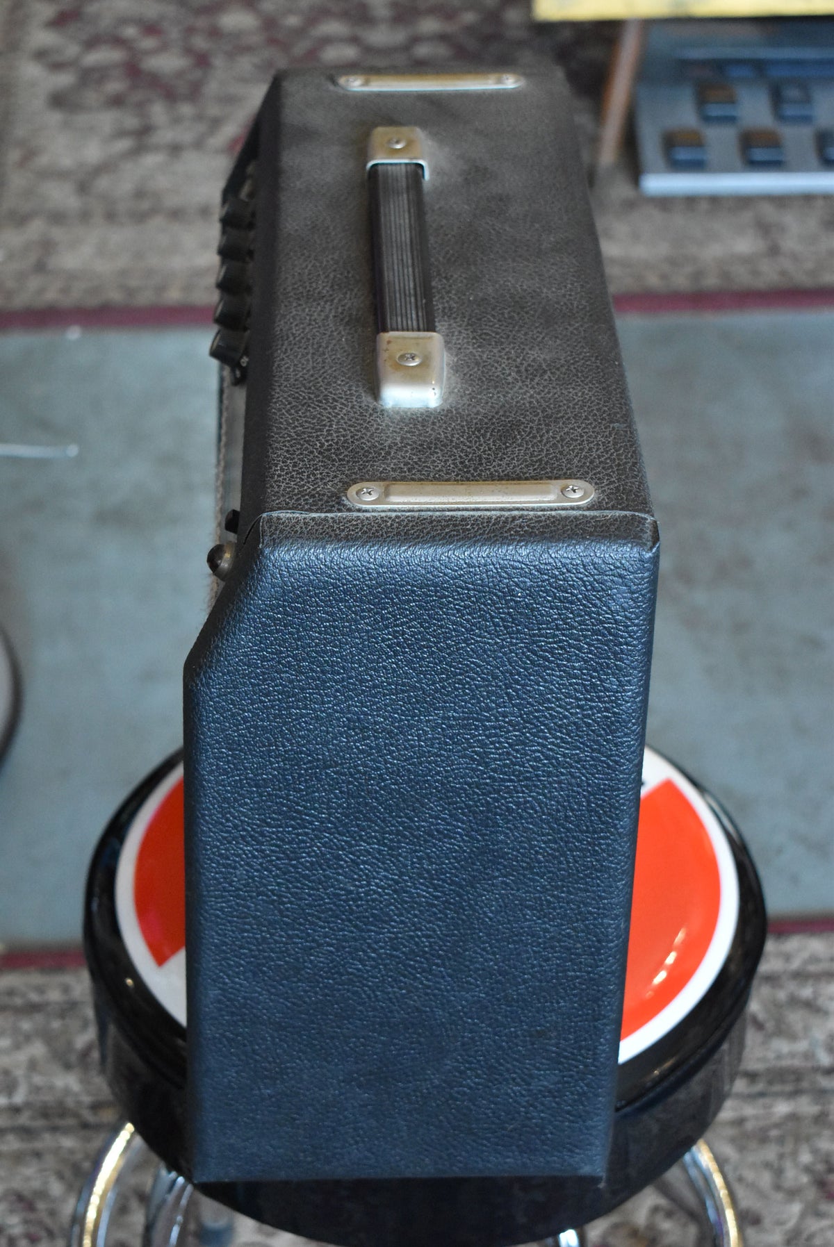 Top-down view of the dark gray textured amp, showing the black handle, chrome hardware, and some control knobs on the left side.