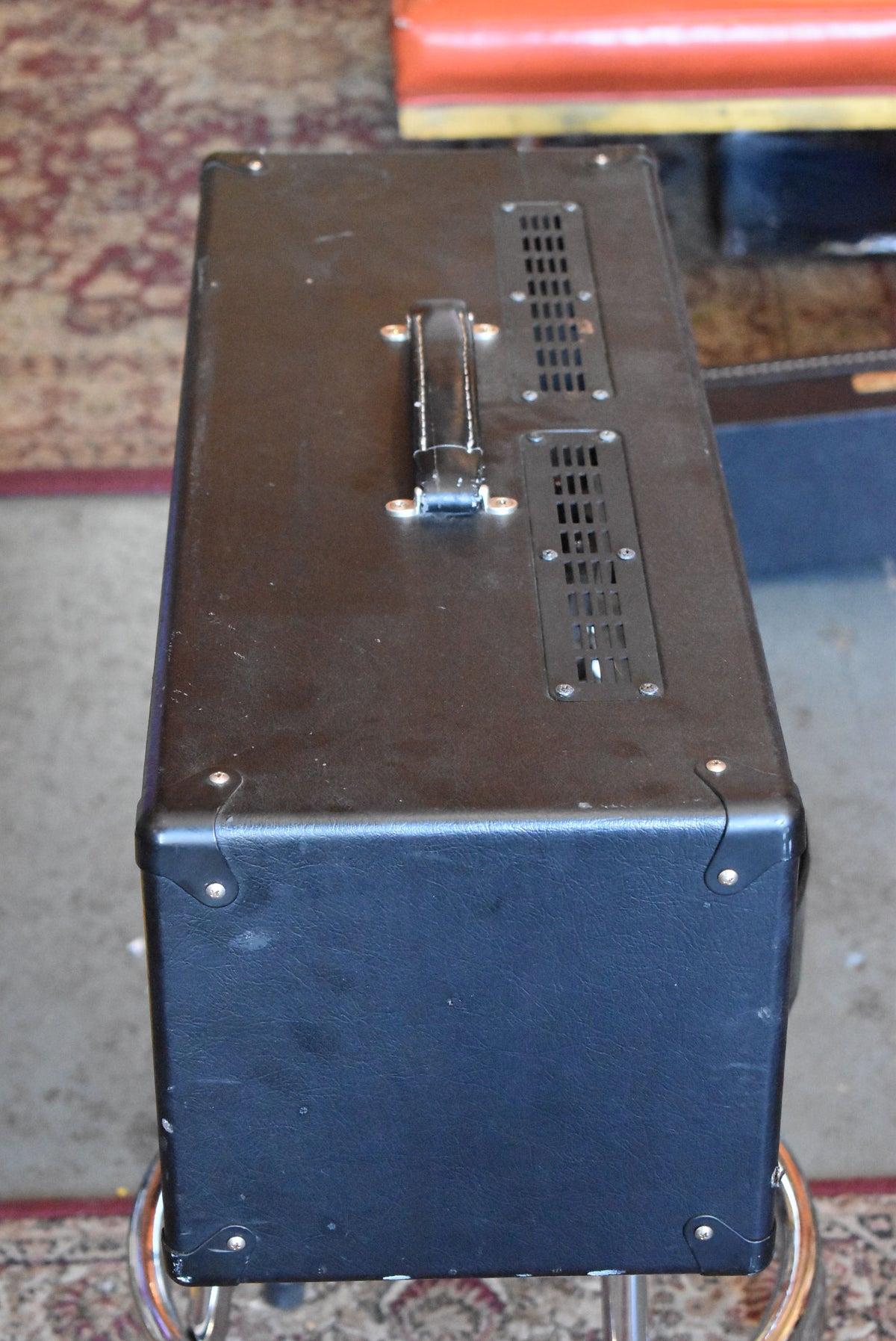 Overhead view of the black tolex amp head, showing the top handle, two vented grilles, and metal corner protectors.