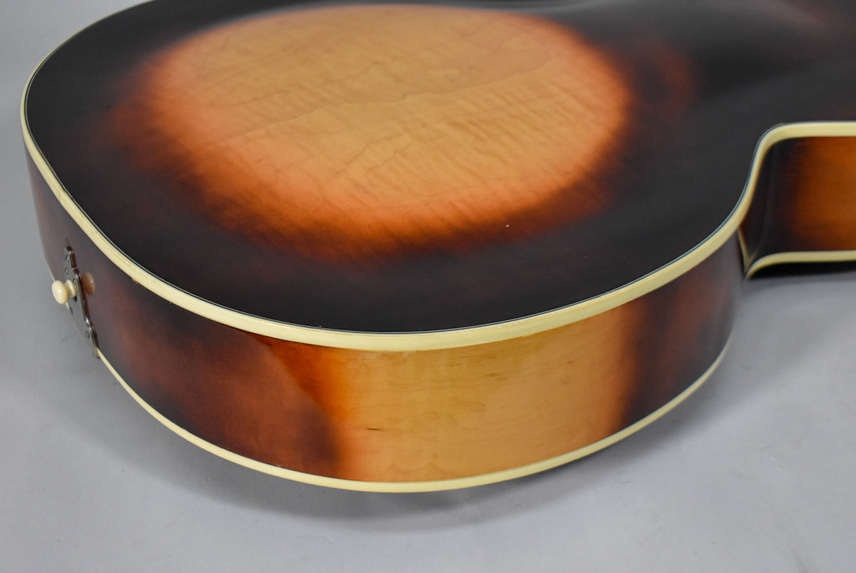 Close-up of the guitar's lower bout and cutaway, showing the sunburst finish, cream binding, and a strap button on the side.