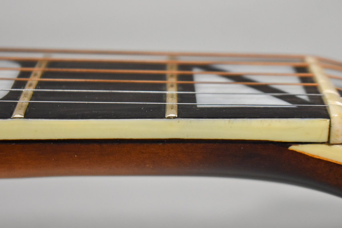 Close-up of the dark fretboard with white block inlays and aged cream binding, showing light wear on the frets.