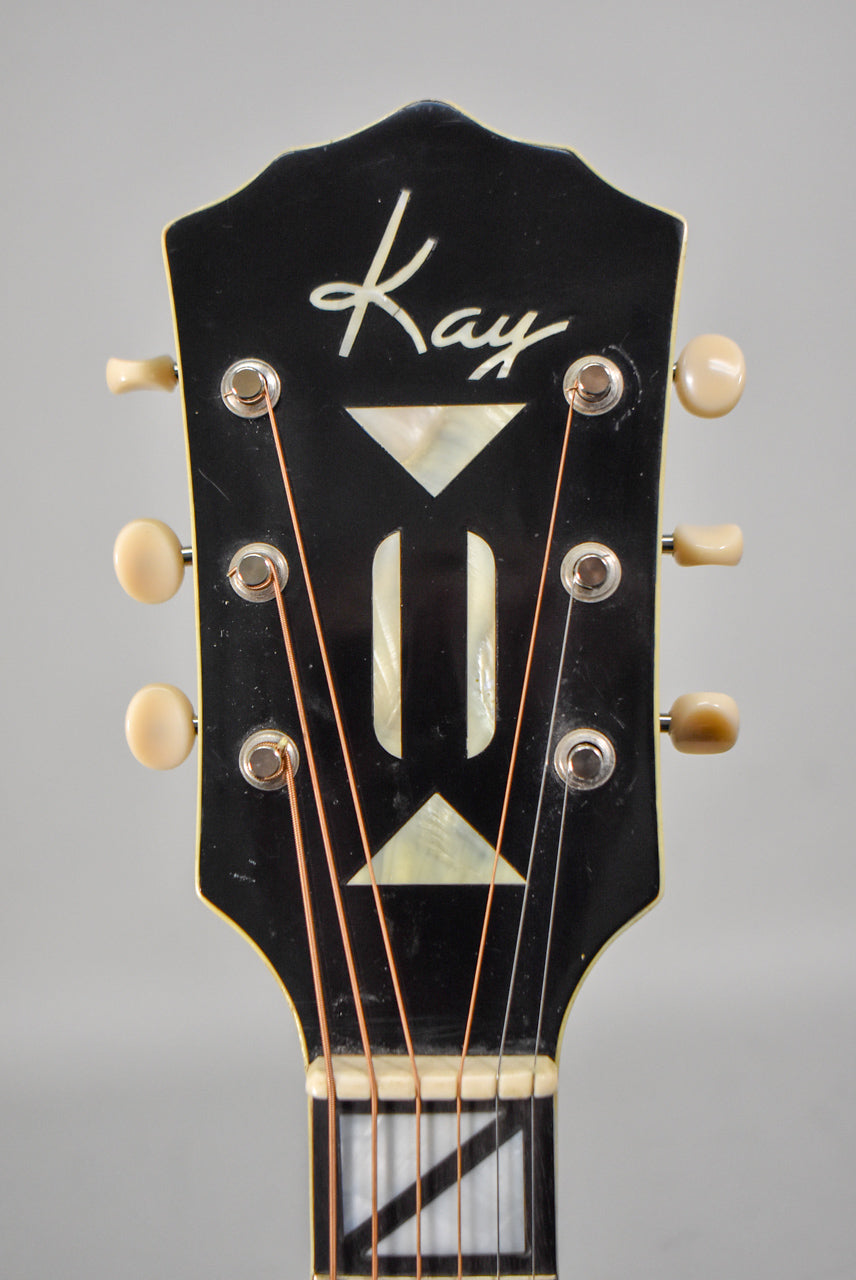 The black headstock features a white script logo, mother-of-pearl inlays, six cream tuning pegs, and light wear.