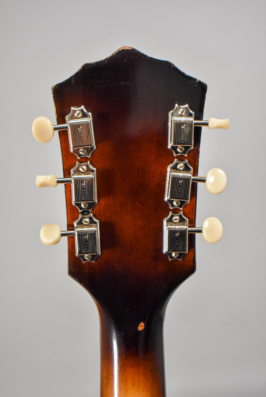 The back of the guitar's headstock and neck, showing six cream-colored tuning pegs, chrome tuners, and finish wear on the edges.