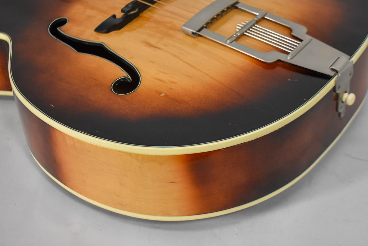 Close-up of the lower bout, showing the sunburst finish, f-hole, and tailpiece, with minor wear and binding visible.