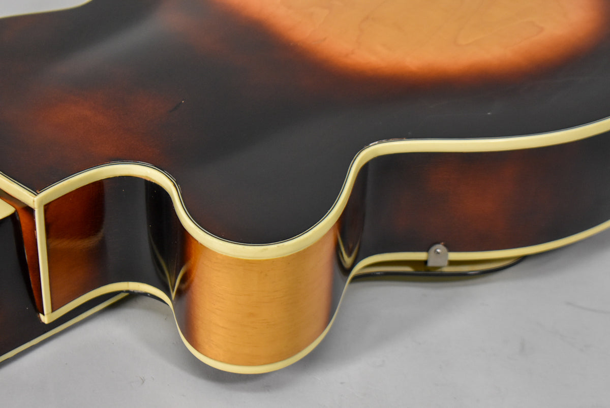 Close-up of the guitar's lower bout, showing the sunburst finish, cream binding, and a small metal strap button on the side.