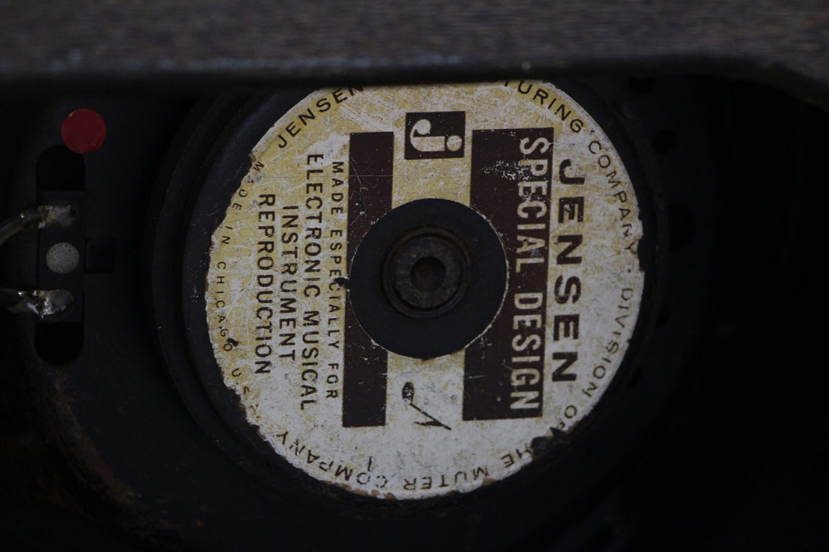 Close-up of a Jensen speaker's worn, off-white label with brown text, showing the central dust cap and exposed wiring.