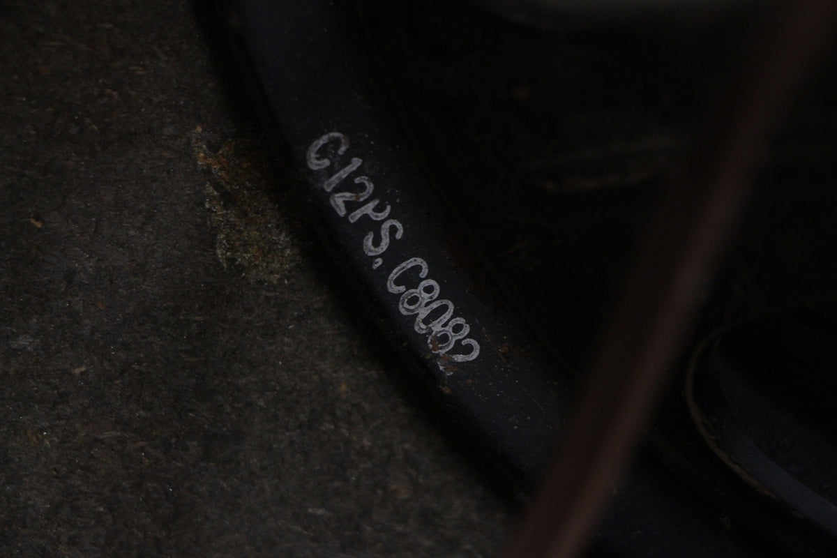Close-up of a dark grey speaker frame with "C12PS.C8082" stamped in white, surrounded by dark, textured material.