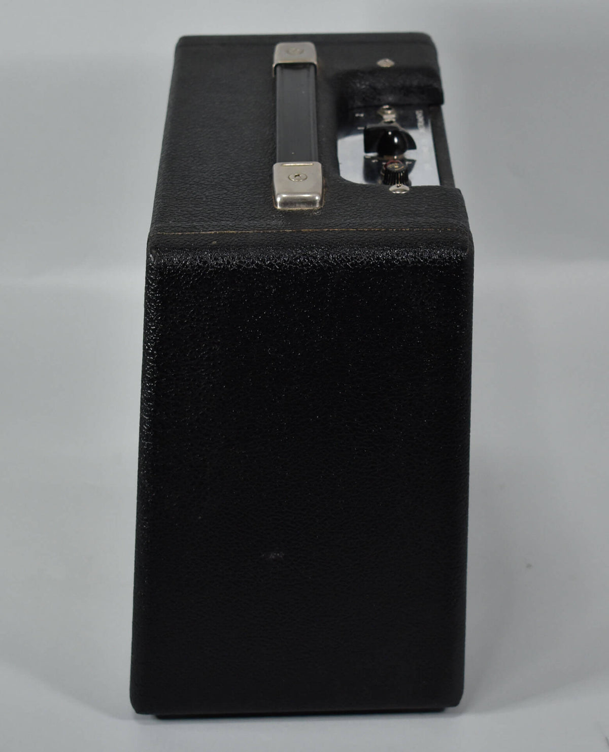 Top-down view of a black guitar amp with a silver handle and control panel with two black knobs.