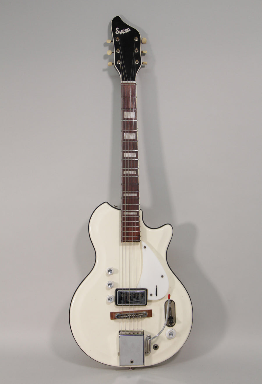 Full-length view of a white electric guitar with a black headstock, chrome hardware, and a white pickguard.