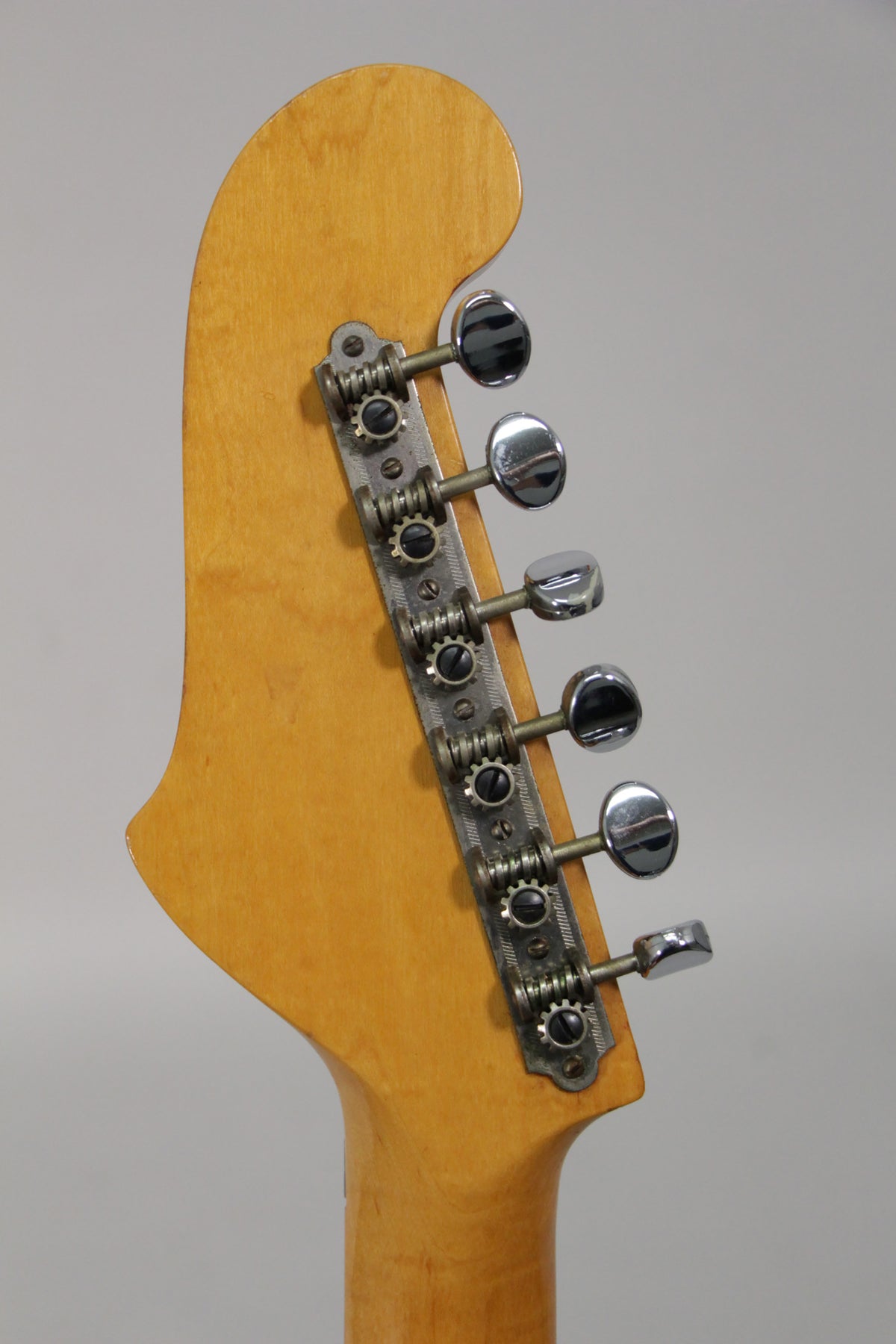 The back of the guitar's headstock and top of the neck, showing six chrome tuners on a metal strip, with light wear on the wood.