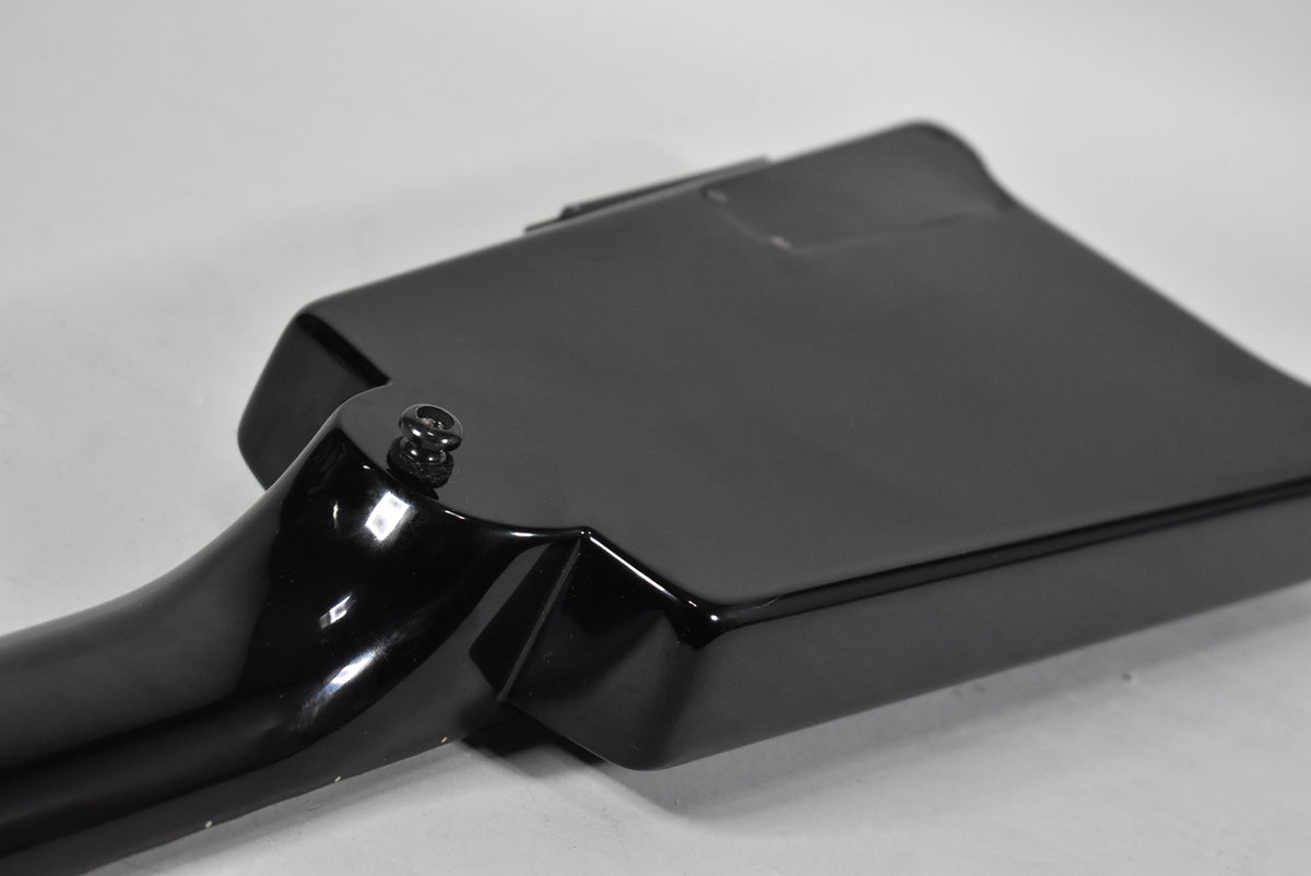 Close-up of the glossy black bass guitar's body and neck joint, showing the strap button and a few minor scuffs on the neck.