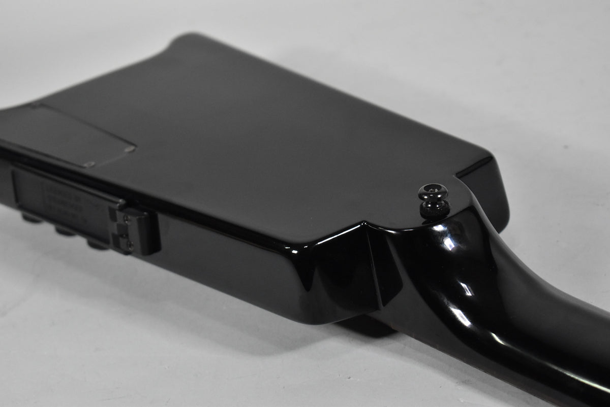 Close-up of the glossy black bass body's upper bout and neck joint, showing a strap button and a small control panel.