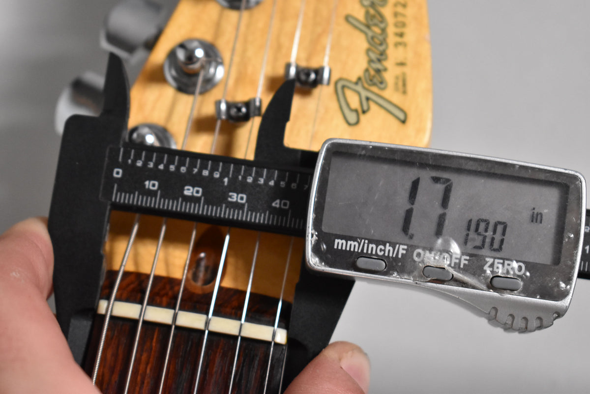 A close-up of the guitar's headstock and nut, with digital calipers measuring the nut width at 1.790 inches.