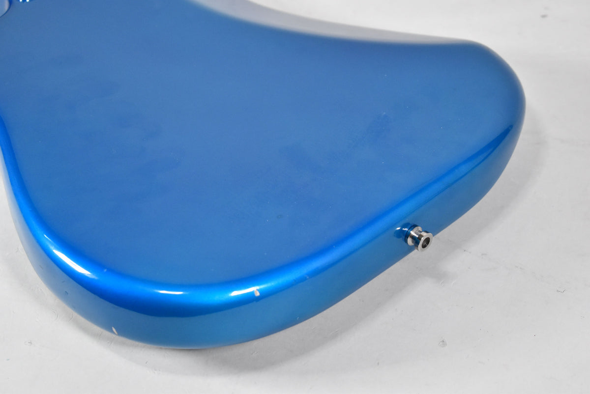The electric guitar's blue body is angled, showing the output jack and some small chips and scratches on the glossy finish.