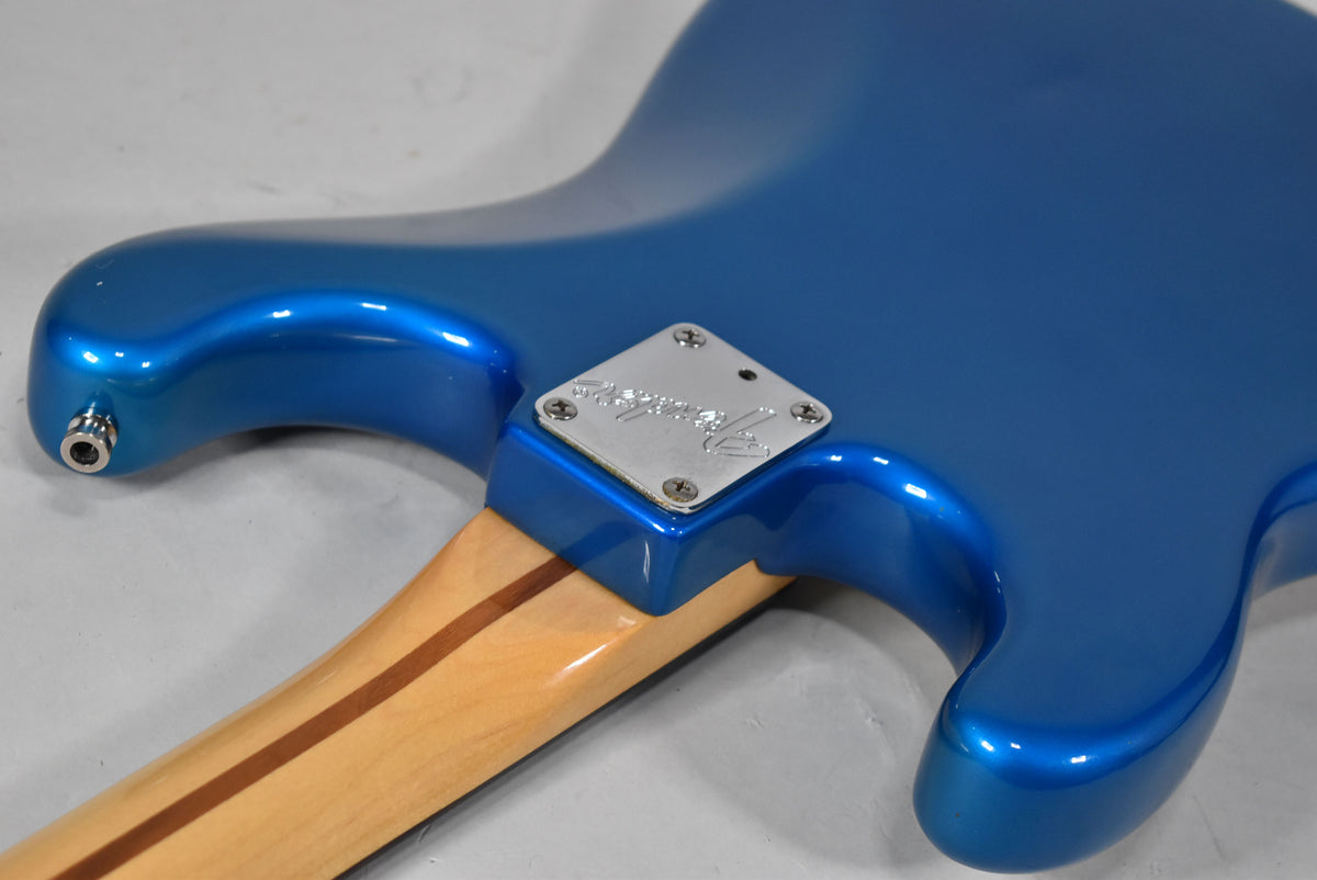 The guitar's blue body and light wood neck meet at a chrome neck plate, with the output jack visible on the lower bout.